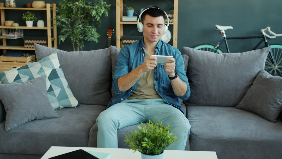 Man wearing headphones plays game on smartphone on phone.